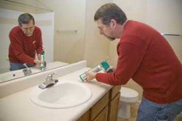 a Cupertino plumbing tech caulks a sink